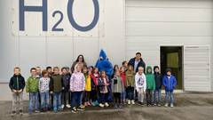 Schüler und Schülerinnen der 2. Klasse Volksschule der Klosterschule Neusiedl stehen vor dem Wasserwerk in Neusiedl mit WLV-Maskottchen TROPFI